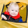 Little boy looking out of yellow tent