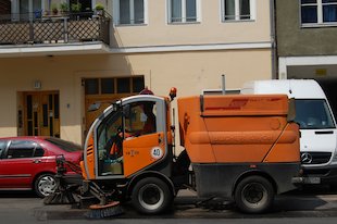 (die) Straßenreinigung, (der) Besen, oranges Gefährt
