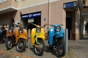 geparkte Mopeds, braun, ocker, gelb, blau, grünes Schloss
