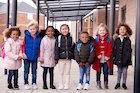 Seven children in winter coats and wearing backpacks