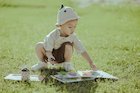 Toddler sitting on the grass playing with a book