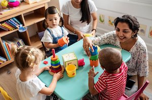 Nursery children playing with teacher in the classroom Nursery children playing with teacher in the classroom